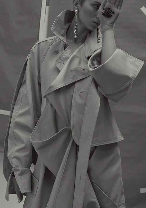 Person wearing a trench coat with a blurred background in Vogue Italia.